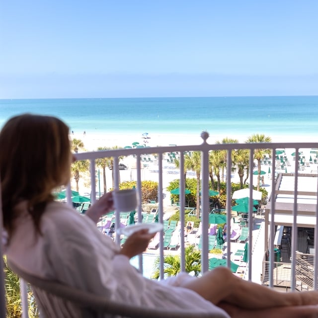 a woman drinking coffee on a balcony