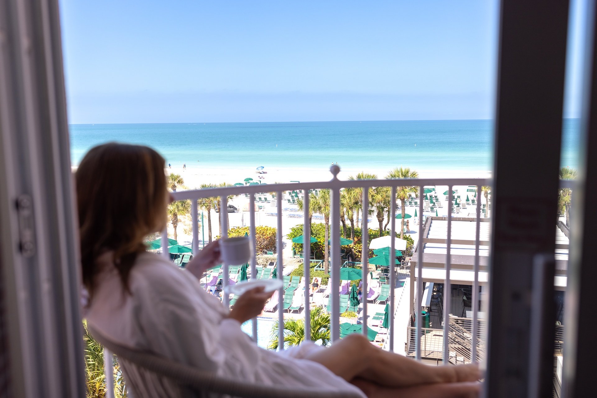 a woman drinking coffee on a balcony