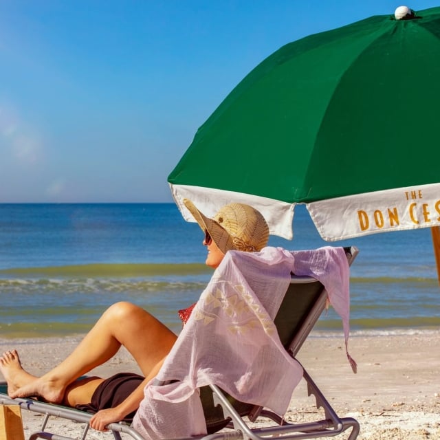 woman sitting on the beach under a green umbrella