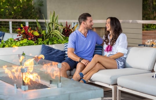 a couple sitting in front of a fireplace enjoying a drink