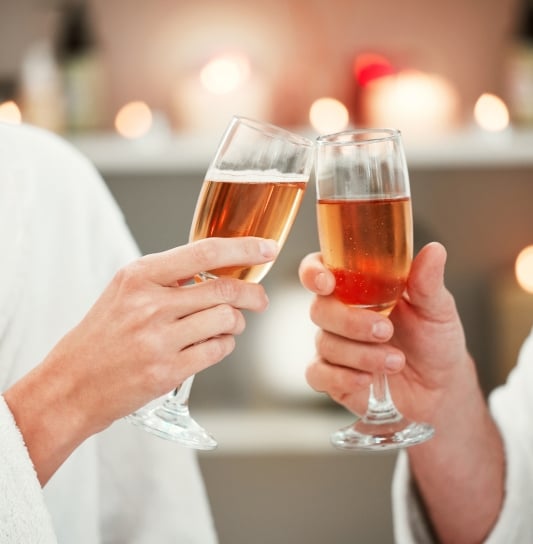 two people tapping glasses of rosé together