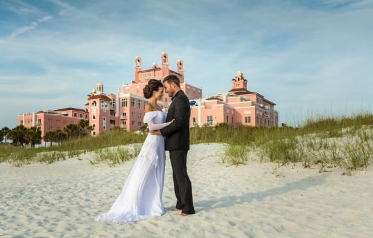 a bride and groom cuddling on the beach