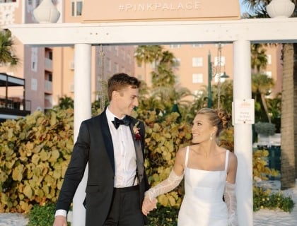 A bride and group holding hands on the beach next to the Don CeSar beach swing