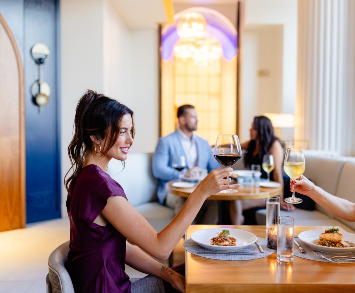 Two women tapping their glasses together while eating dinner