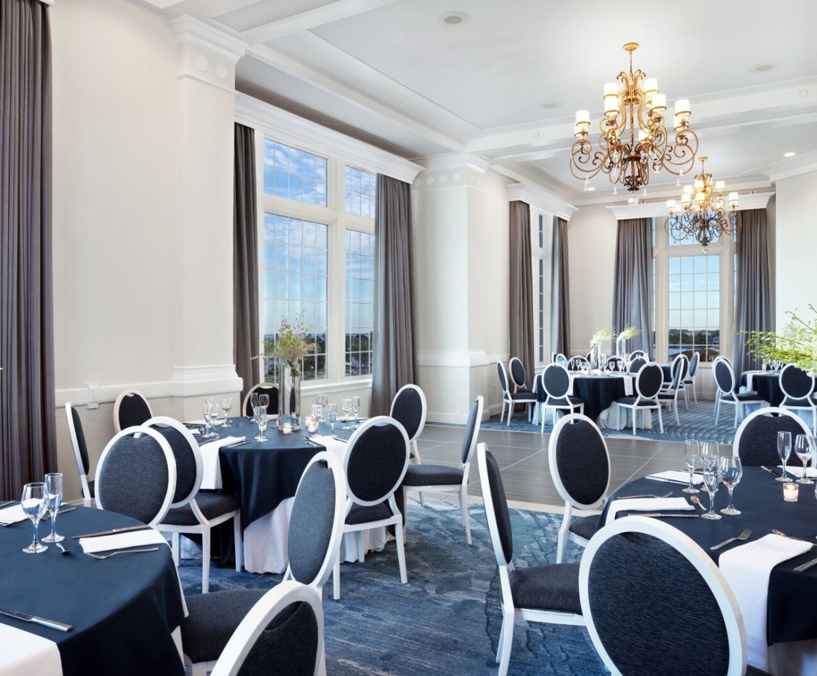 A spacious banquet room featuring blue tablecloths and white serviettes elegantly arranged on the tables.