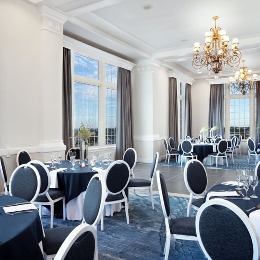 A spacious banquet room featuring blue tablecloths and white serviettes elegantly arranged on the tables.