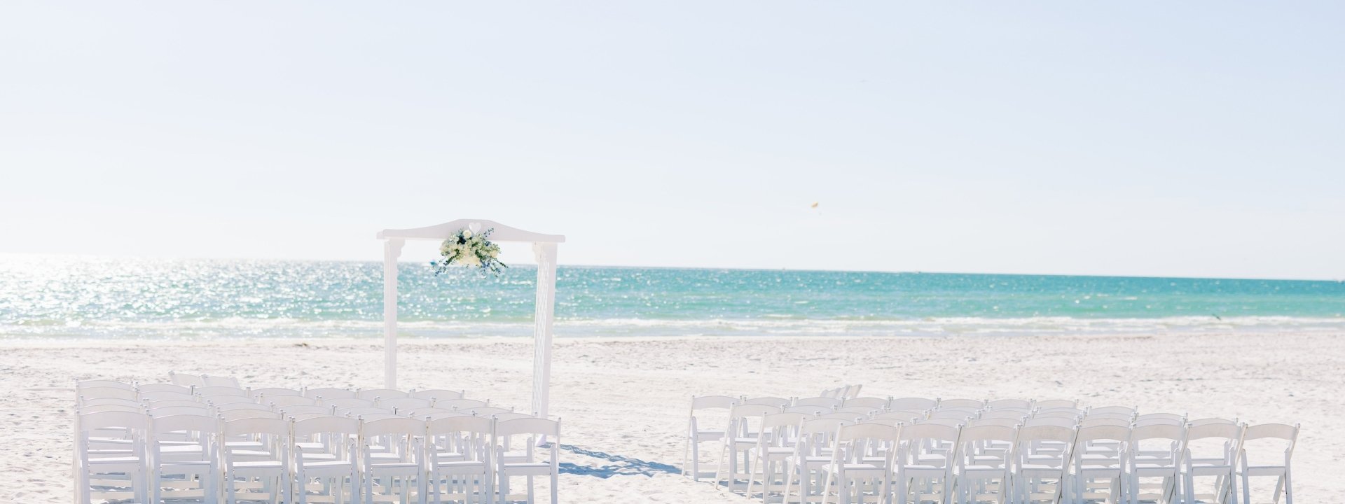 white alter and chairs set up on the beach