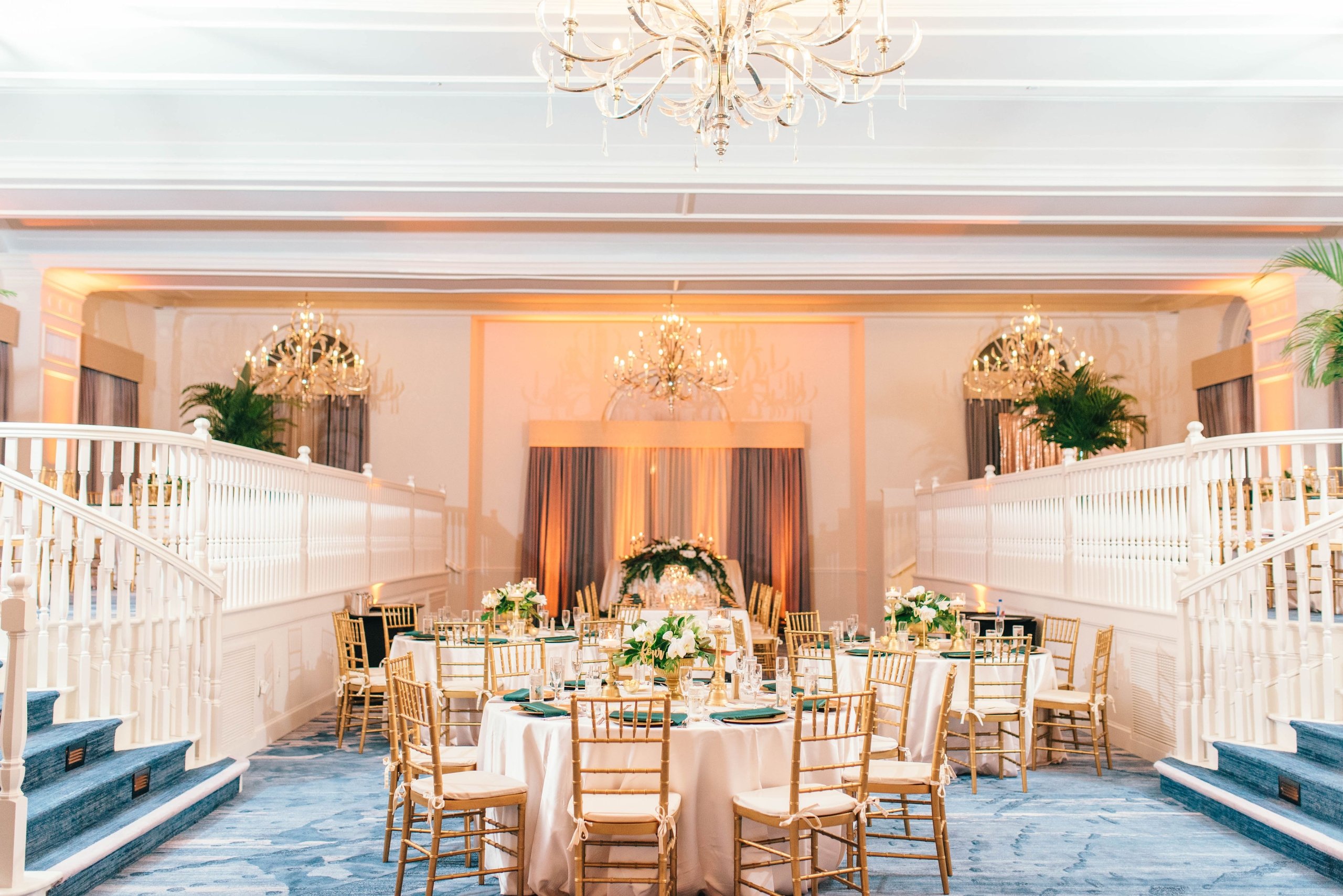 A luxurious wedding reception featuring a blue carpet and elegant chandeliers in a beautifully decorated room.